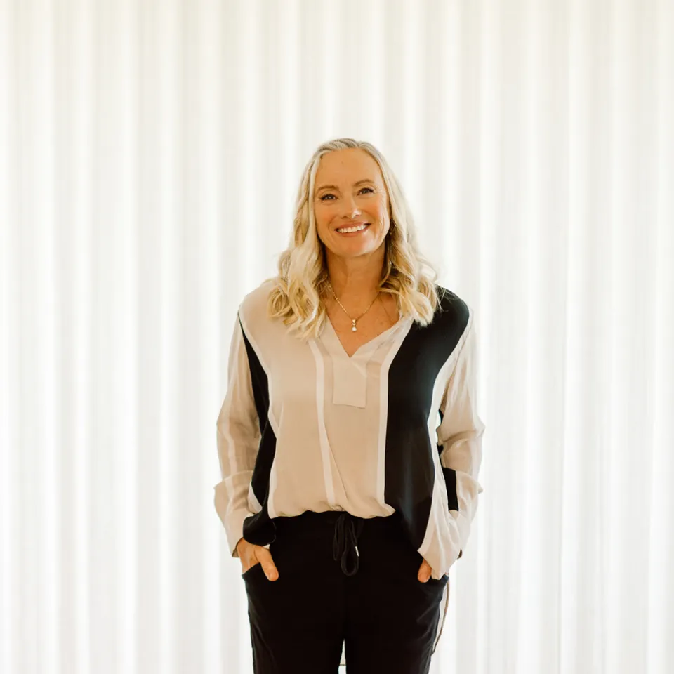Cyndi standing in front of a white curtain, hands in pockets