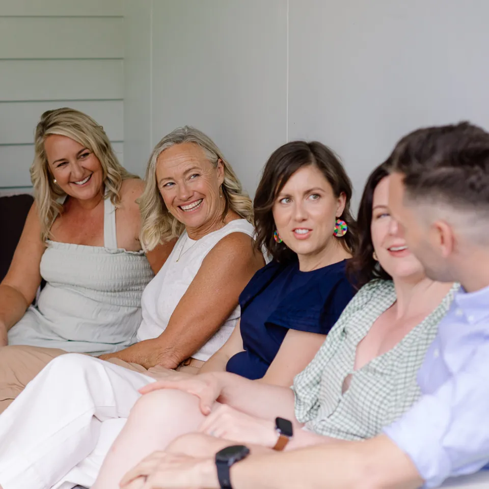 Cyndi laughing on a couch with four members of her team